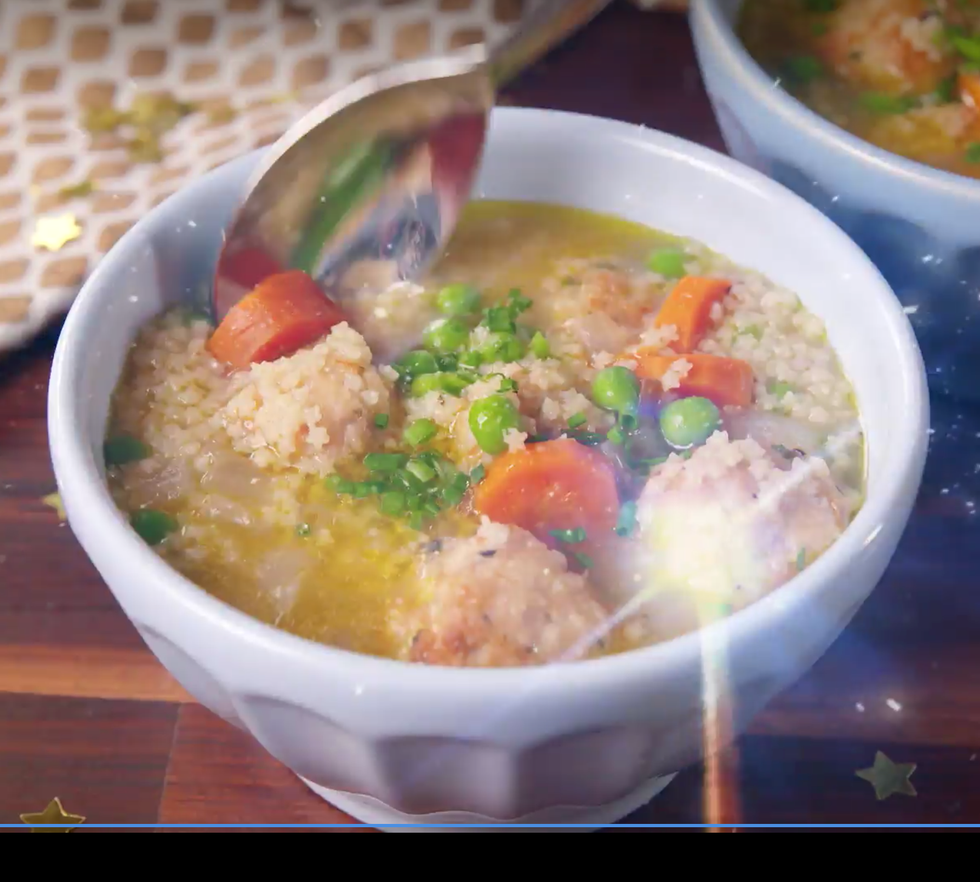a white bowl of galaxy noodle soup being spooned