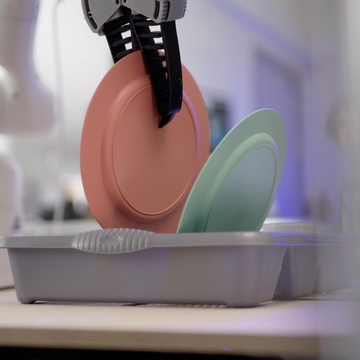 dyson household chore robot gripping a pink plate with a green plate resting in a drying rack on the right side