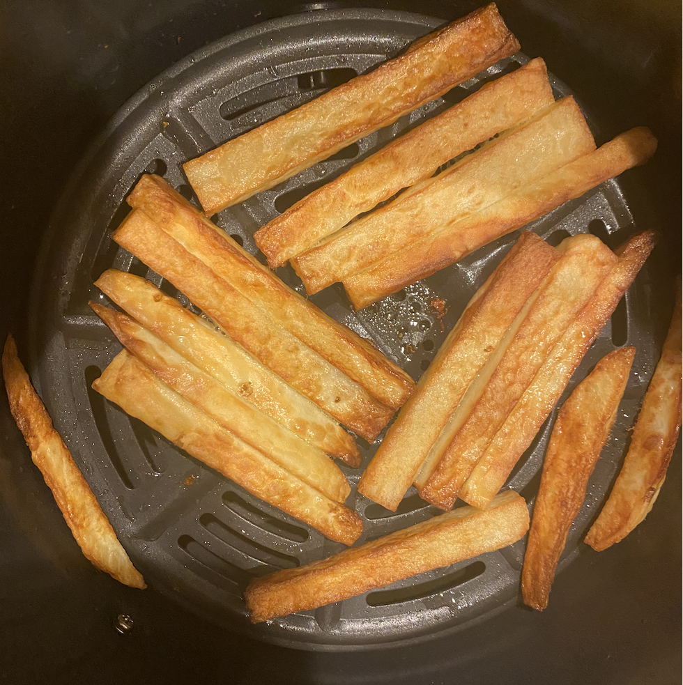 overhead shot of the cooking basket of the ninja air max xl air fryer which contains mostly golden brown hand cut french fries