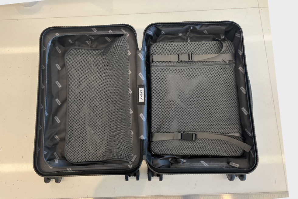 an empty away carry on laid open flat on a white table, good housekeeping's luggage review