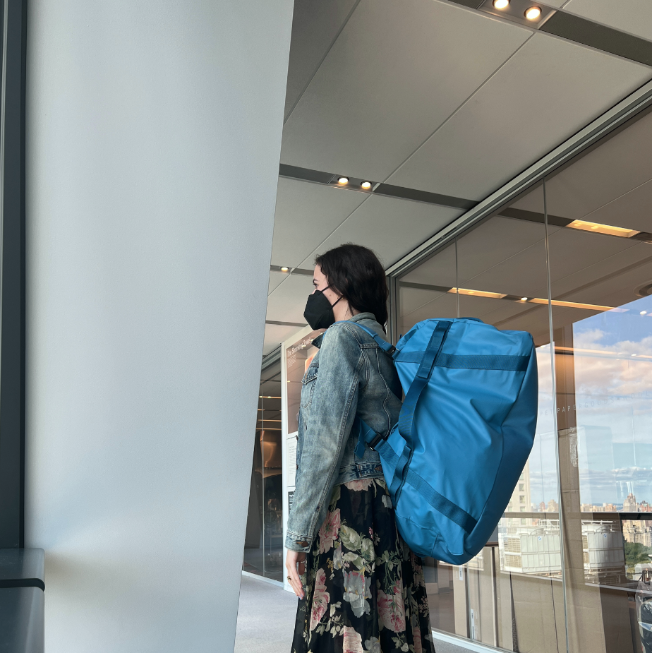 a gh analyst is wearing a blue duffel as a backpack as part of good housekeeping's testing to find the best duffel bags