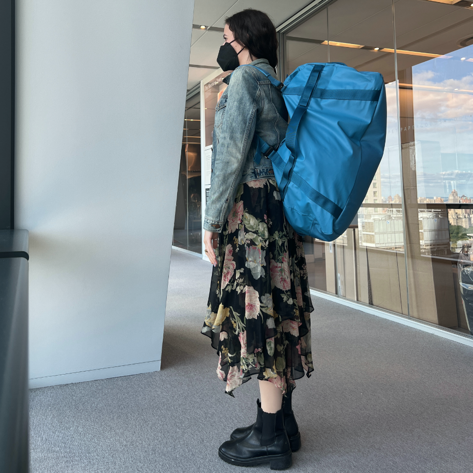 a gh analyst is wearing a blue duffel as a backpack as part of good housekeeping's testing to find the best duffel bags