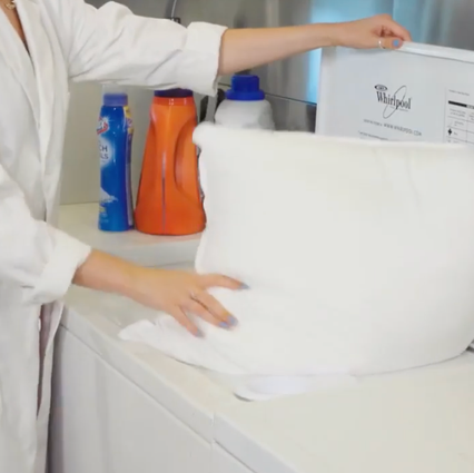 best down pillows - testing image a good housekeeping analyst putting a pillow in the washing machine, good housekeeping's testing for the best down pillows
