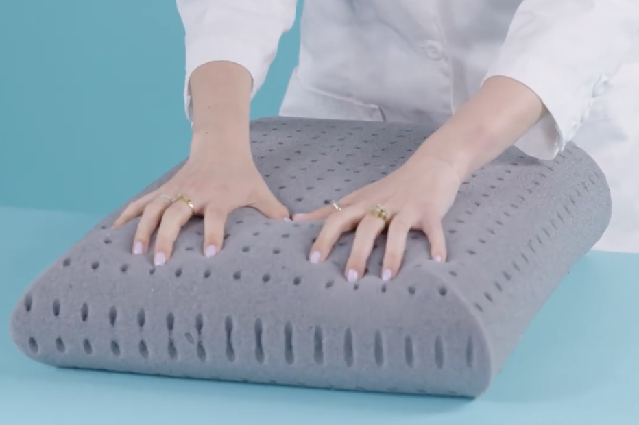hands pushing down on tuft and needle foam insides as part of good housekeeping's pillow testing