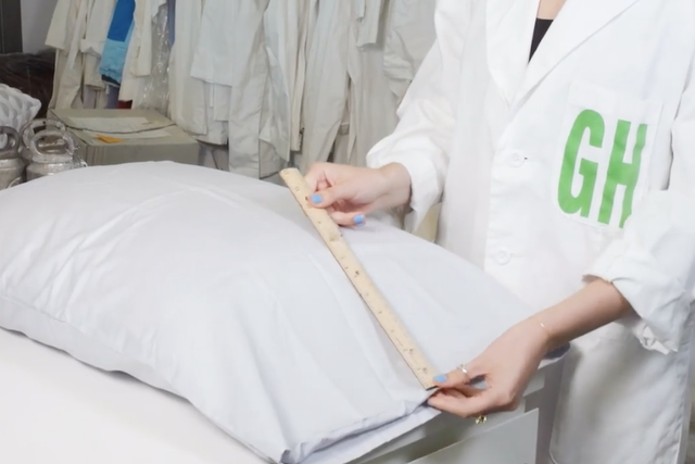 an analyst measuring a pillowcase with a pillow inside, part of how good housekeeping tests pillows