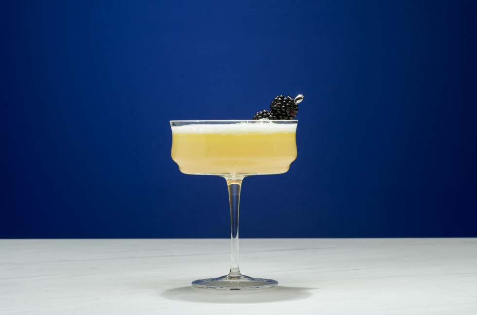 a glass of yellow liquid with a black insect on top