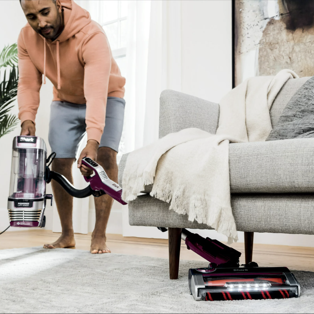 a man vacuuming under a couch