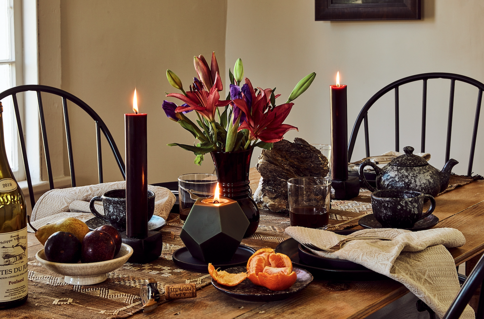 a table set with candles and flowers and plates with a moody dark color scheme