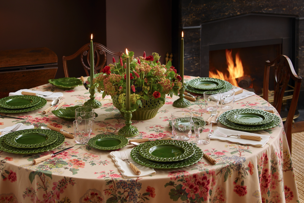 a table set with green plates and candlesticks