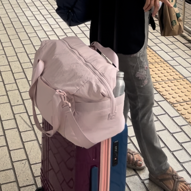 a pink bagssmart weekender bag on a rolling suitcase while traveling, good housekeeping's best weekender bags