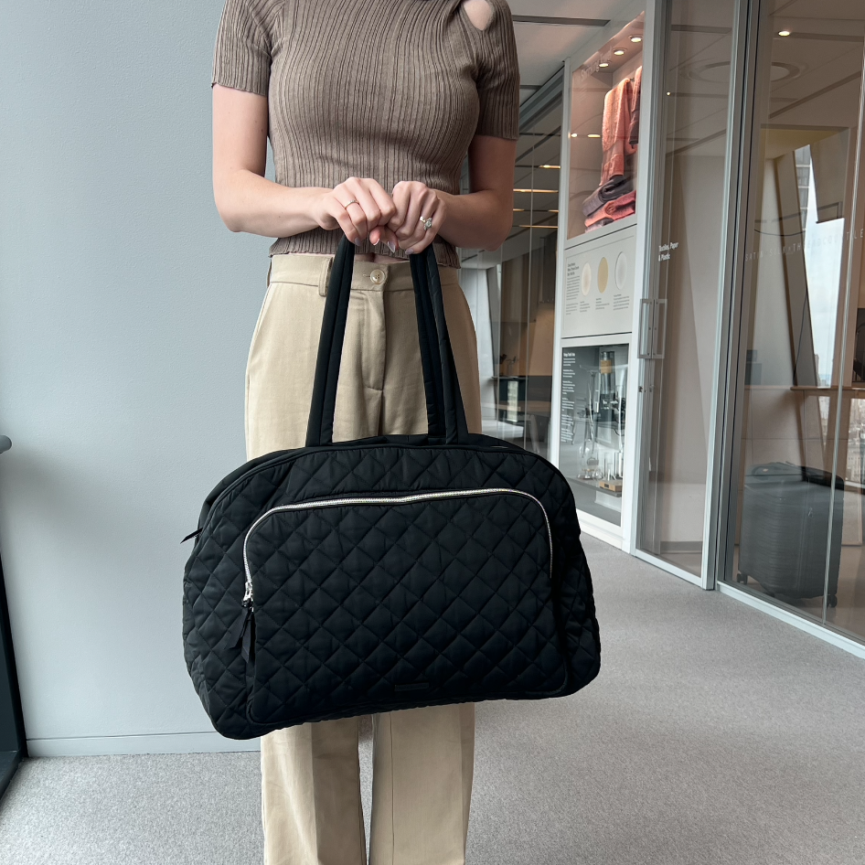 a model carrying a black vera bradley grand weekender travel bag, good housekeeping's best weekender bag testing