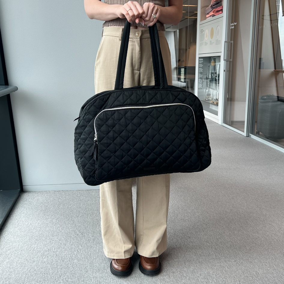a model carrying a black vera bradley grand weekender travel bag, good housekeeping's best weekender bag testing