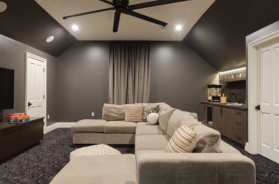 a large living room with dark walls, a large couch and a fan