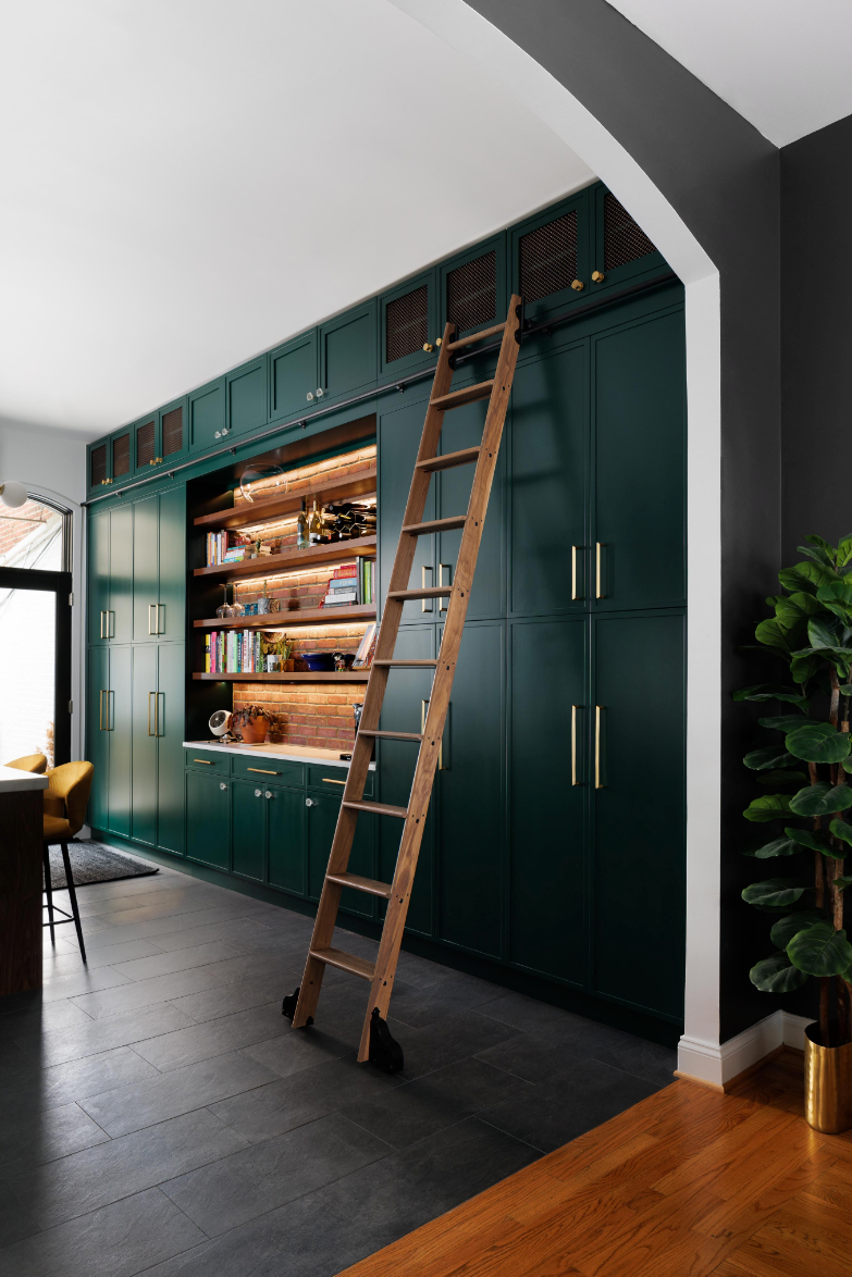 a ladder leaning against dark green kitchen cabinets