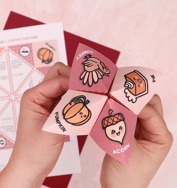 paper origami fortune teller with a turkey, pie slice, pumpkin, and acorn on it