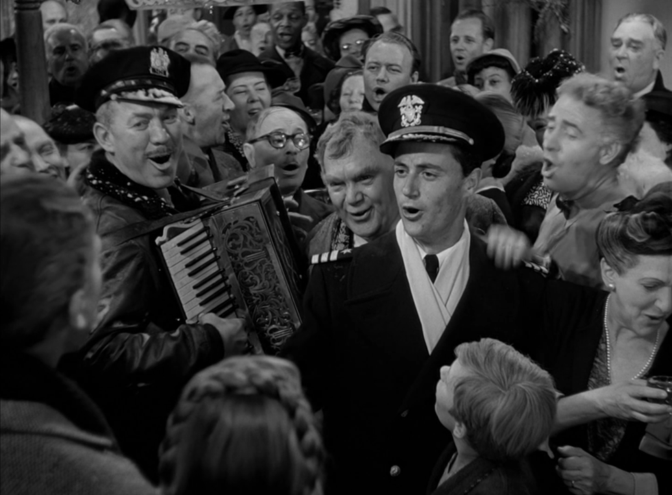 a person in a suit and hat holding an accordion in front of a crowd