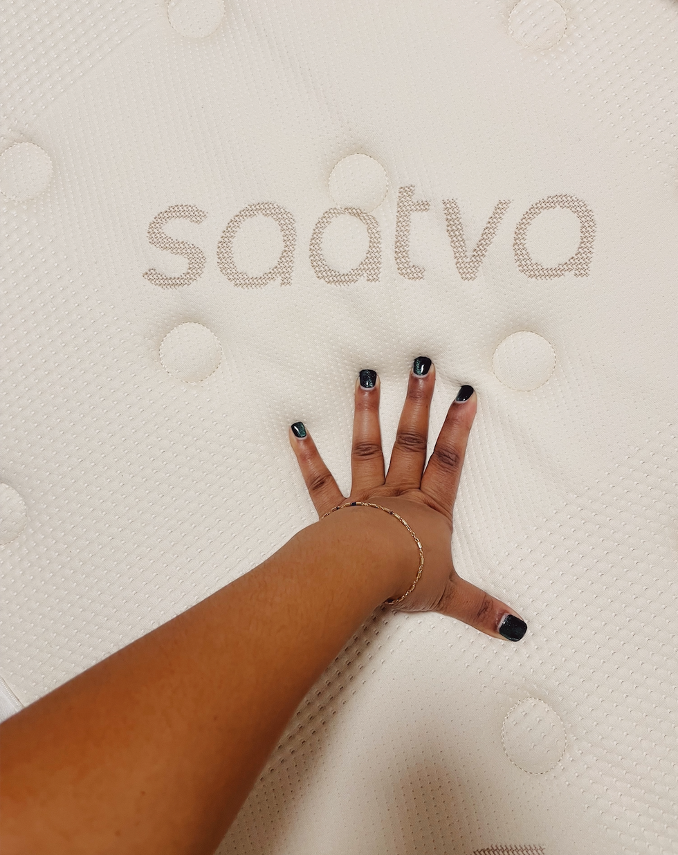 a mão de uma mulher com unhas pretas em um quadro branco