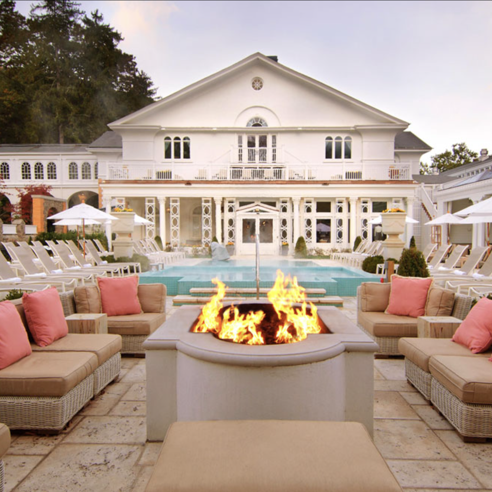 a large white building with a large pool and a large patio with a fire pit