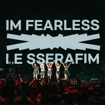 le sserafim performing at coachella with the words i'm fearless on the screen behind them
