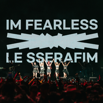 le sserafim performing at coachella with the words i'm fearless on the screen behind them