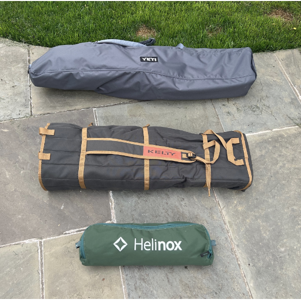 three carrying cases in grey, black and green on a sidewalk, for carrying camping chairs