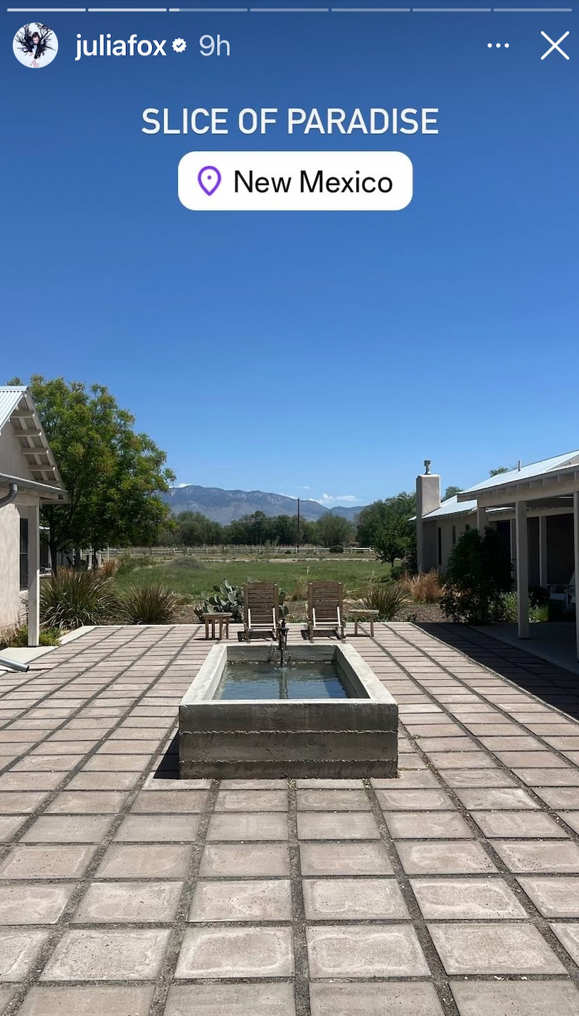 a brick patio with a stone circle and a stone circle with a building and trees and mountains in