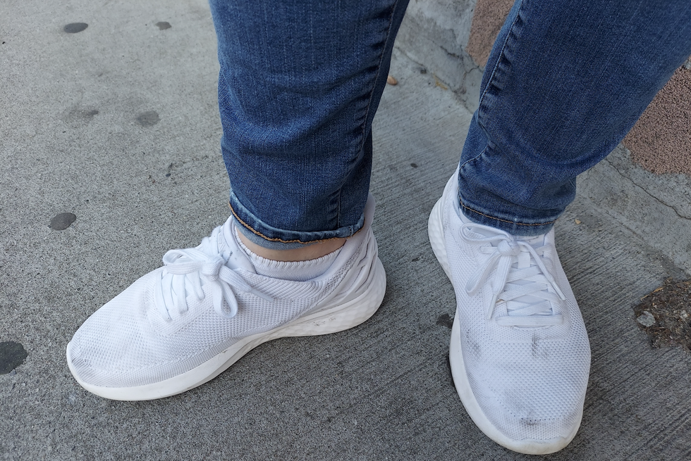a tester wearing a pair of white kizik athens sneakers on a sidewalk, good housekeeping's best walking shoes