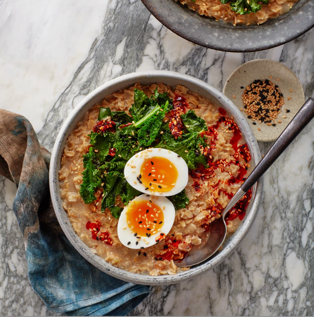 savory miso oatmeal bowl with jammy eggs and greens in a bowl with a spoon