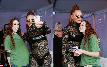 two individuals taking a selfie at an event with a backdrop of a tent