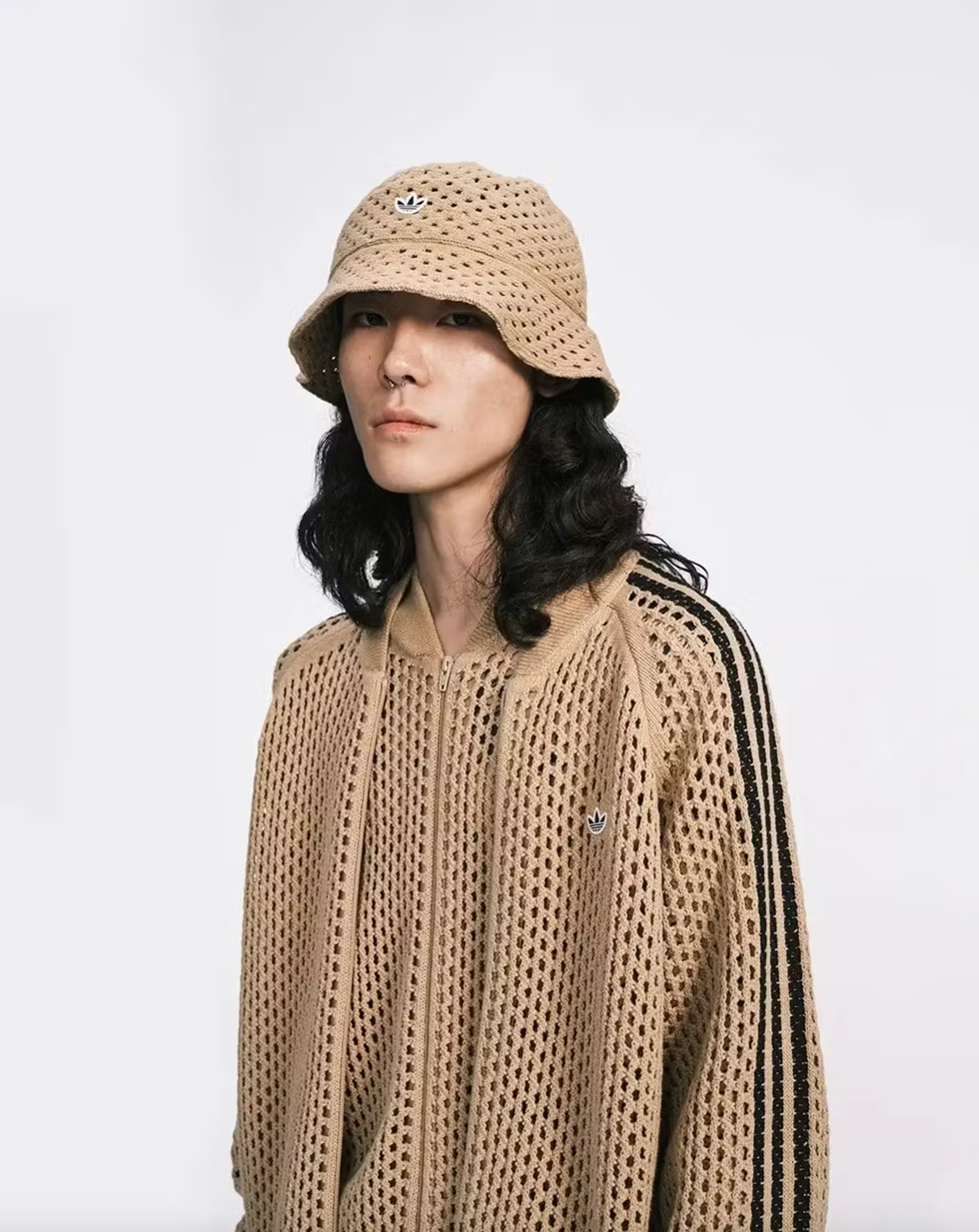 person wearing a beige knitted sweater and bucket hat