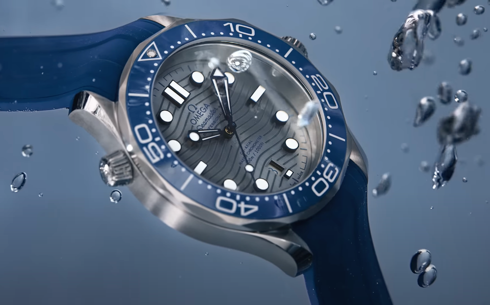 a luxury diving watch submerged in water with visible droplets