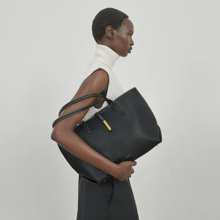 best carry on totes a person holding a large black tote bag with a gold accent