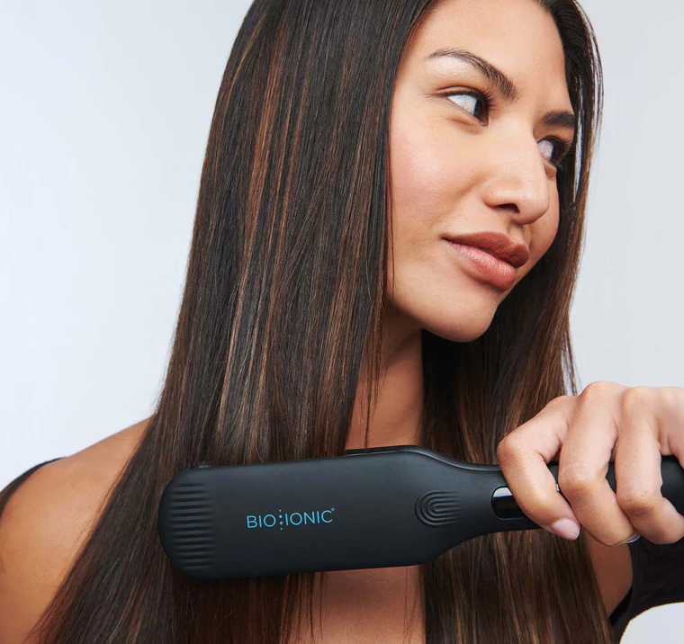 a person holding a hair straightener while styling their hair