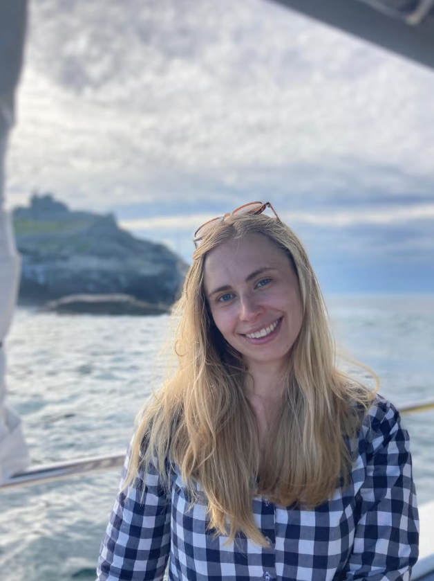 person wearing a checkered shirt on a boat with ocean and coastline background