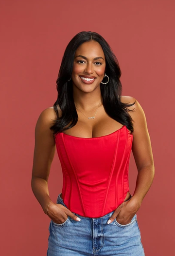 a woman wearing a red corset and denim shorts standing against a solid background