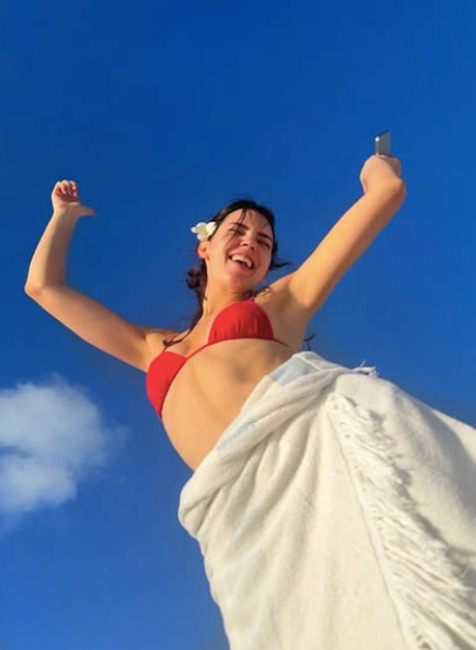 person posing with arms raised against a clear blue sky