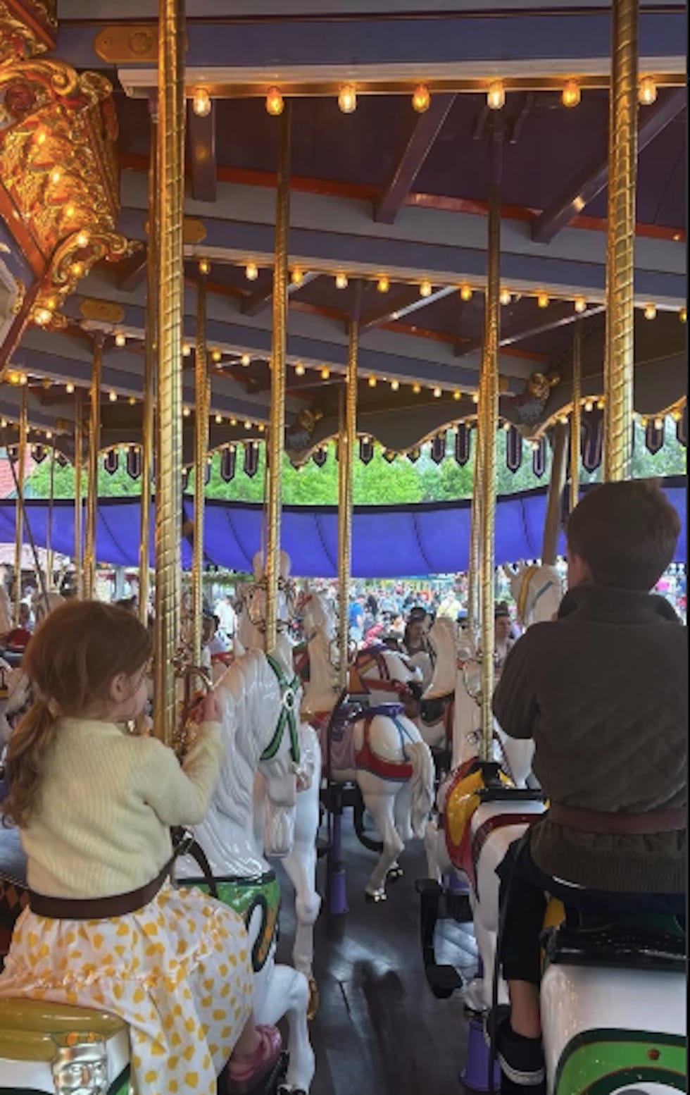 enfants montant sur un carrousel avec des chevaux blancs et des décorations colorées