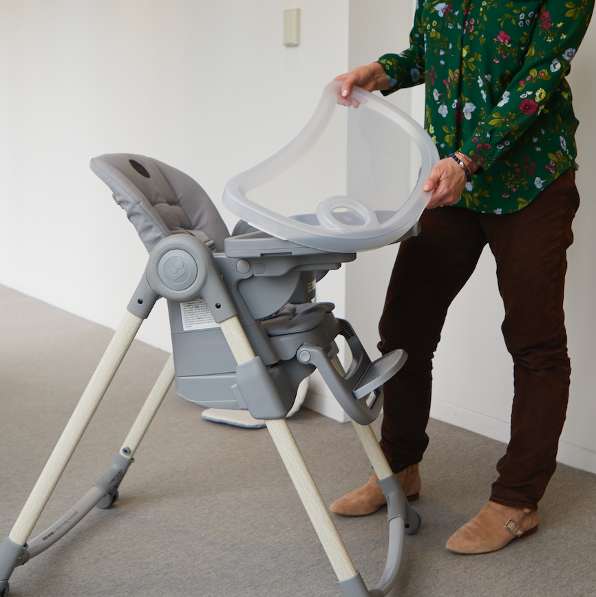 a tester demonstrates a tray within a tray on a baby's high chair