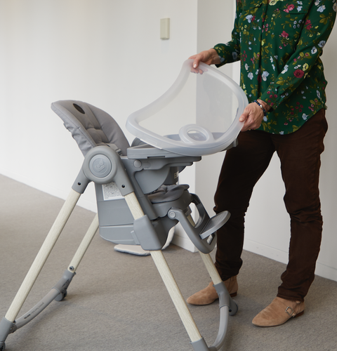 a tester demonstrates a tray within a tray on a baby's high chair