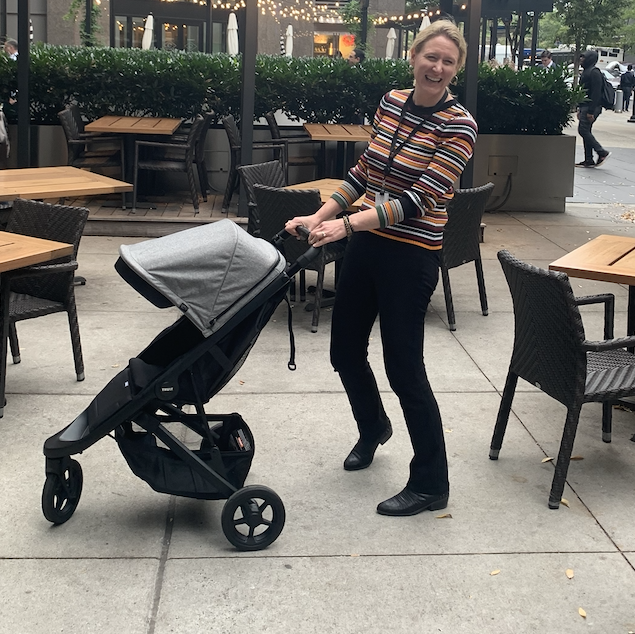 a woman tests a lightweight thule spring stroller outside of a restaurant, part of good housekeeping's tests for best lightweight strollers