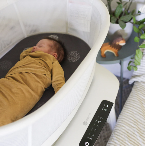 4moms mamaroo sleep bassinet, with a baby sleeping inside while wearing a dark yellow sleeper in a bedroom, a good housekeeping pick for best bedside bassinet