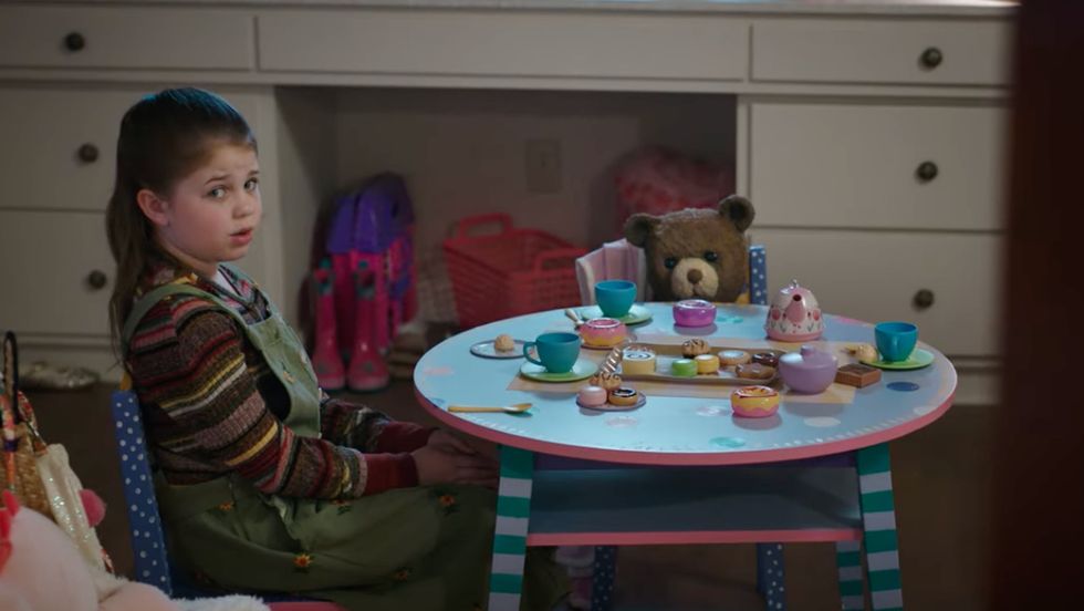 a girl sitting at a table with a plate of cupcakes