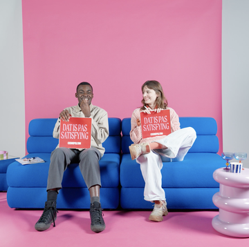a man and a woman sitting on a couch holding a sign
