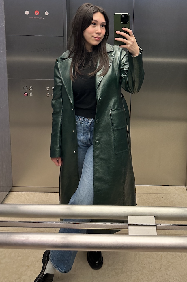 a gh editor wearing a green coat from nuuly taking a mirror selfie in an elevator
