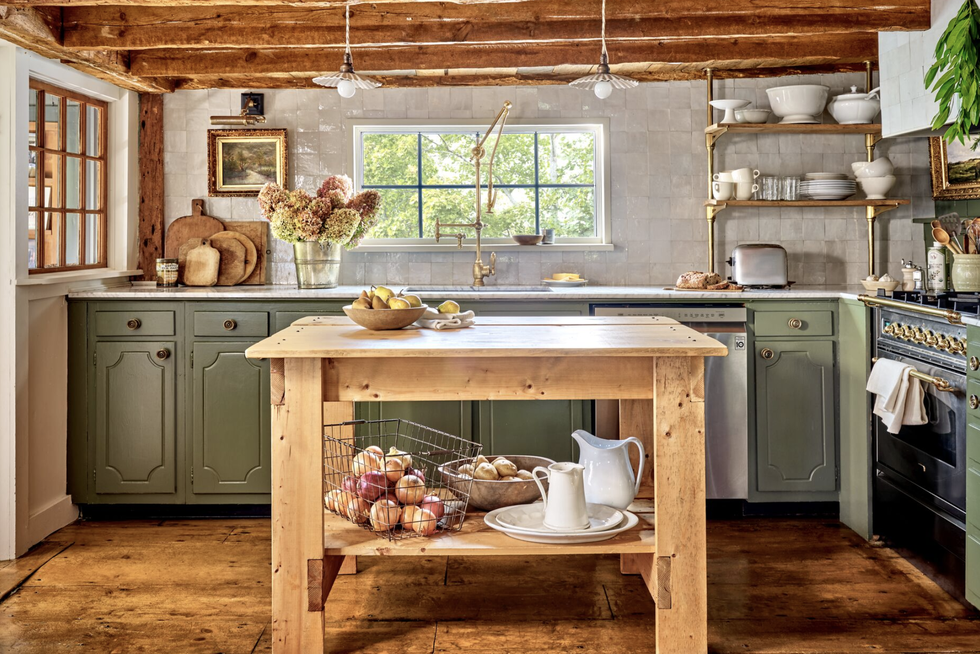 low ceiling green kitchen with rustic beams and a natural wood island and white tile backsplash