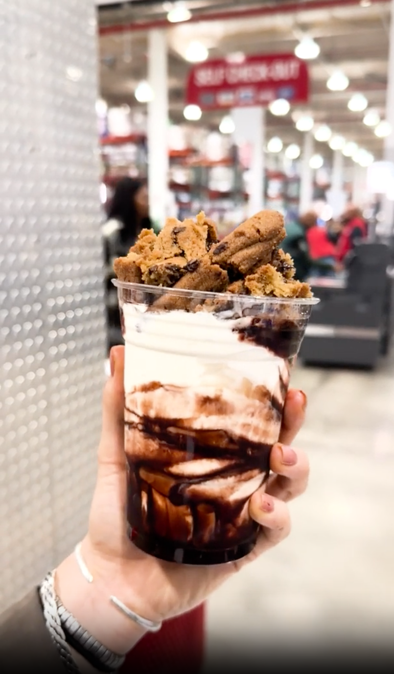 a hand holding a cup of ice cream with a scoop of ice cream