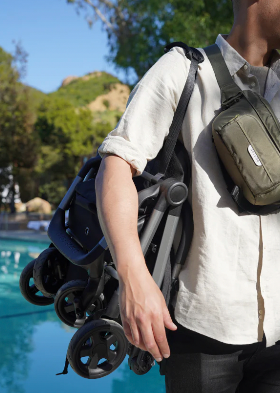 a man carried the colugo compact stroller on his shoulder
