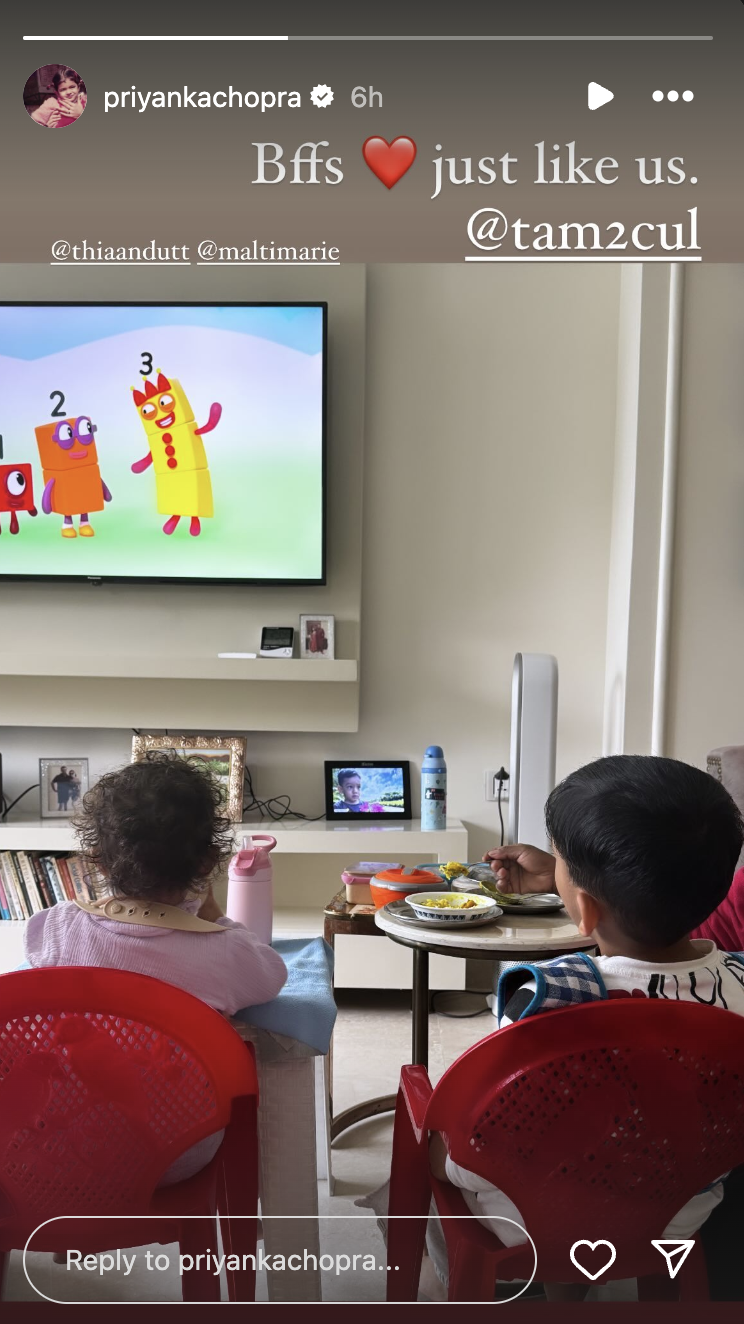 a group of kids sitting at a table watching a tv