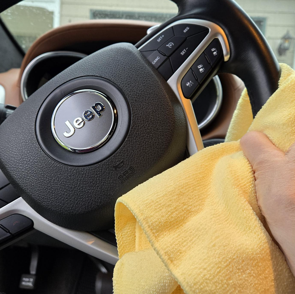 a hand wiping a steering wheel with a cloth