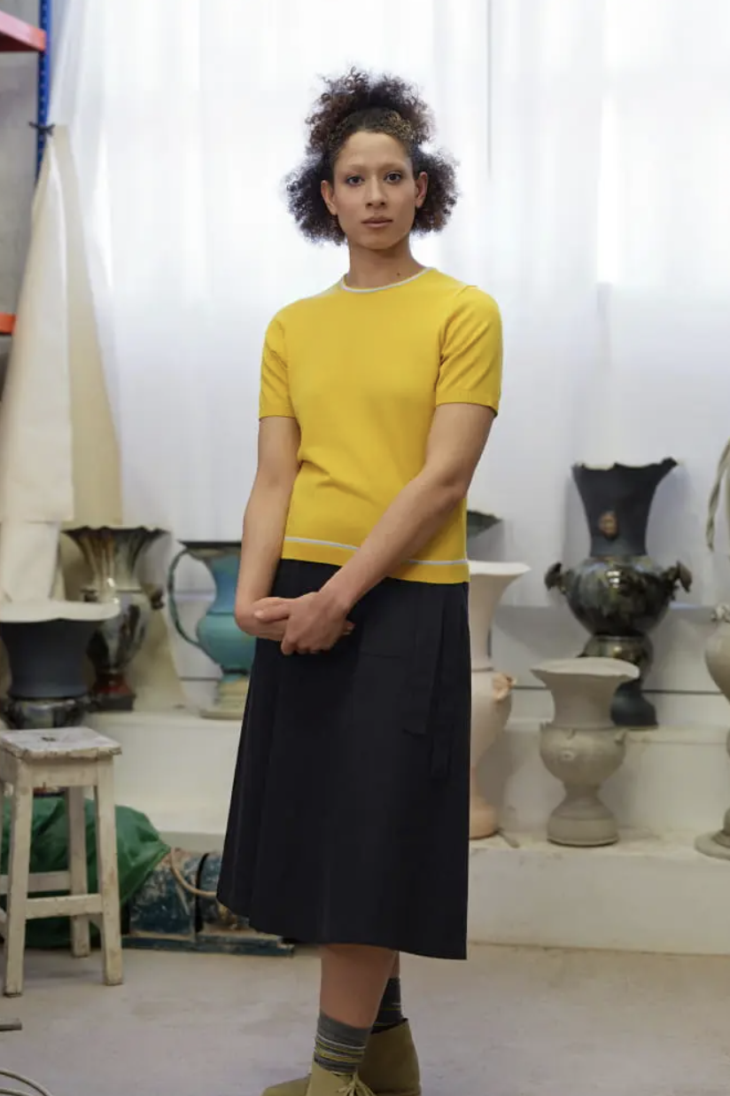 a woman wearing a yellow shirt and skirt